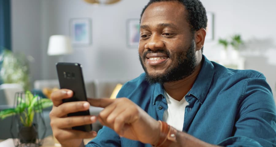 Man in his home navigating an app on his cell phone